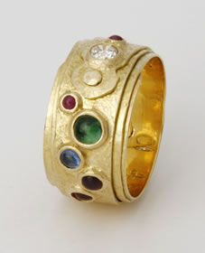 Coiled ring in 18K gold with seven stones including a diamond